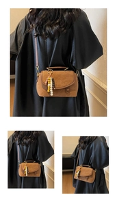 Close-up of retro brown suede crossbody bag with colorful bead charm and top handle