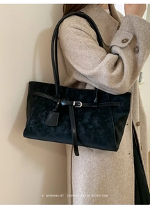 Close-up of minimalist black matte suede tote bag worn with a beige cashmere coat