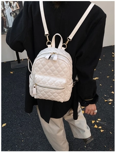 Détail d'un sac à dos blanc matelassé avec motif à losanges et fermetures dorées