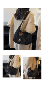 Detail of black matte shoulder bag featuring white contrast stitching and a fur ball charm