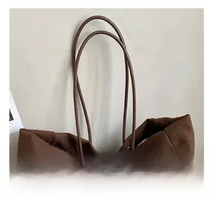 Detail of slim brown leather handles on a large matte tote bag with neat stitching