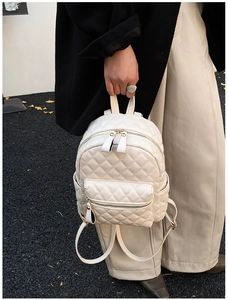 Close-up of white quilted mini backpack featuring elegant diamond stitching and gold hardware