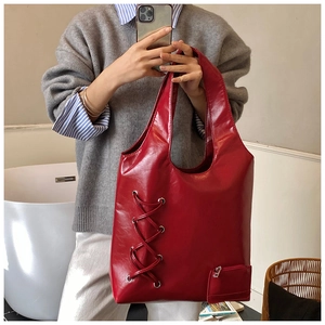 Detailed view of red large-capacity tote bag in glossy PU leather with lace-up metal eyelets