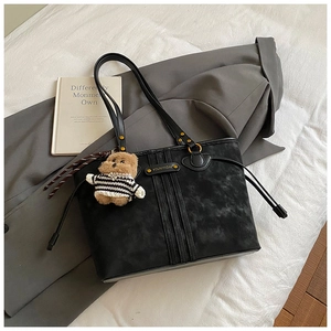 Détail du sac cabas en daim noir avec boucles dorées et breloque ourson rayé mignonne