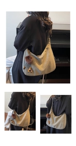 Detail view of large olive green suede hobo bag with decorative plush ball pendant