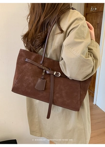Side view of deep brown suede tote bag styled with a minimalist beige trench coat