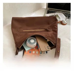 Interior storage of brown suede shoulder bag showing tablet and daily essentials
