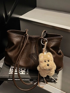Sac fourre-tout en cuir marron foncé avec pendentif chiot peluche sur décor urbain