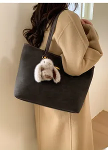 Détail du grand sac cabas en daim gris avec bandoulière et pendentif lapin blanc