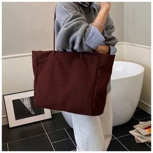 Detail of burgundy large tote bag with slim leather straps shown in a lifestyle scene