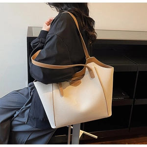 Close-up of beige litchi grain leather tote bag with brown straps worn on shoulder