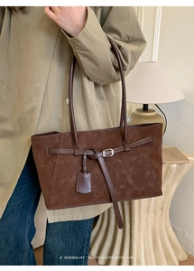 Detailed macro view of dark brown faux suede tote bag with leather straps and silver buckle
