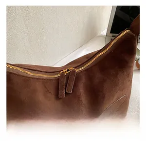 Detailed macro view of the premium golden double zippers on the dark brown suede bag