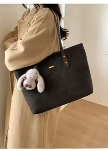 Détail du grand sac cabas en daim gris foncé avec bandoulière et breloque lapin