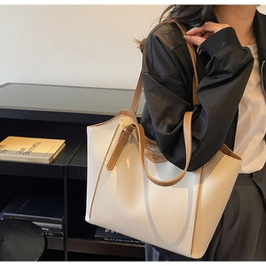 Detail of cream pebbled leather tote bag with brown straps and logo patch on model