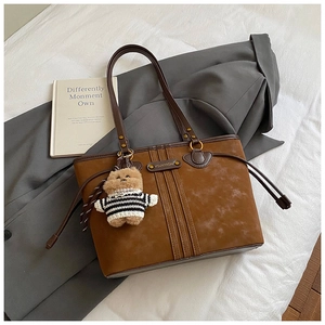 Détails de texture du sac cabas en daim marron avec surpiqûres et charmant petit ours en peluche