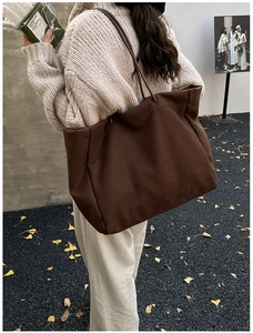 Outdoor lifestyle shot of a large brown canvas tote bag held by a model in autumn