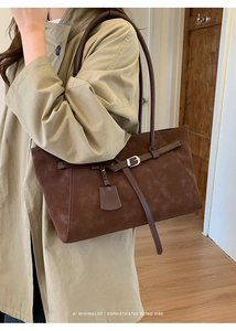 Detail of dark brown faux suede tote bag with silver buckle and decorative pendant strap