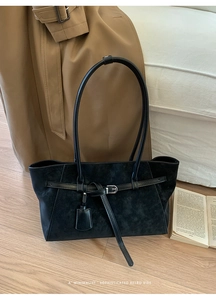 Minimalist black tote bag in suede and smooth leather on a warm autumn wooden floor