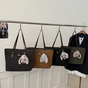 Série de sacs cabas en daim marron, noir et vert avec un pendentif lapin en peluche