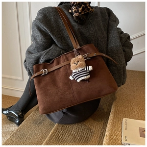 Dettaglio della borsa tote in pelle scamosciata marrone con cinturini e ciondolo a forma di orso