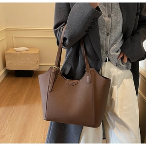 Detail of brown litchi pattern leather tote bag worn with a stylish grey blazer coat