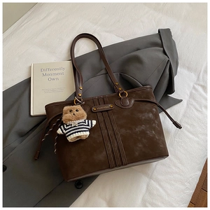 Détails du sac fourre-tout marron foncé avec coutures, dorures et breloque ourson
