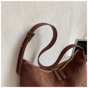 Detail of adjustable strap and gold dual zipper on brown suede tote bag for women