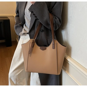Close-up of khaki tote bag with litchi texture and brown handles on a stylish model