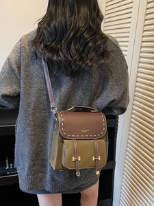 Retro color-block backpack in olive green and brown leather shown on a model back view