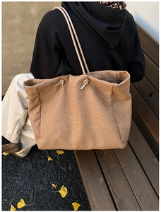 Detail of camel wool tote bag with drawstring handles in an autumn outdoor setting