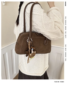 Detail of dark brown suede shoulder bag with contrast stitching and plush bear charm