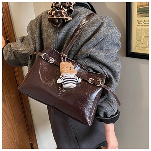 Détail d'un sac à bandoulière vintage en cuir ciré marron avec boucles et peluche ours