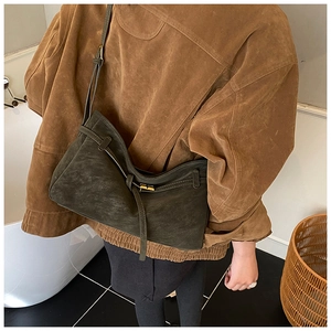 Vue latérale du sac fourre-tout en daim vert foncé avec boucle dorée et lanière