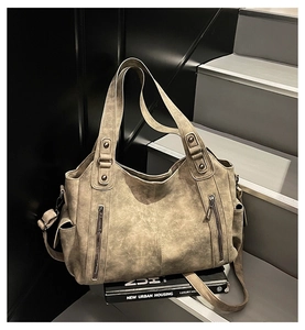Detail view of large tote bag featuring vintage leather texture and front zip pockets