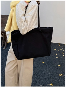 Detailed shoulder view of a large black vintage tote bag worn by a model in a fall setting