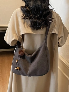 Minimalist large dark gray suede hobo bag with white stitching and fuzzy ball pendant
