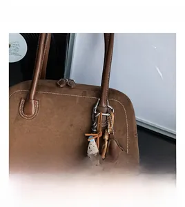 Detail of brown suede Boston bag featuring vintage twin handles and bear star charm