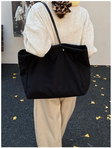 Rear street view of a large black minimalist canvas tote bag styled for autumn fashion