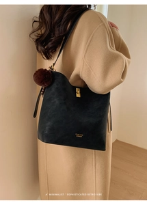 Gros plan du fermoir doré et du pompon sur le sac seau en cuir noir mat élégant