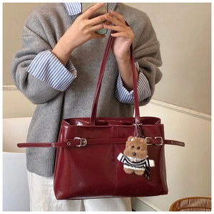 Détail du sac à main bordeaux en cuir brillant avec pendentif ours et boucle de ceinture
