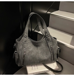 Close-up of matte leather texture and decorative zippers on a dark grey tote bag