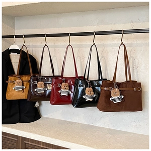 Sacs à bandoulière variés en cuir verni et suède avec breloques d'ours suspendus sur un rack
