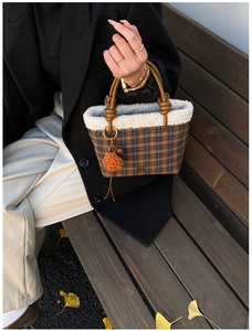 Detail of plaid wool handbag with white faux fur trim and brown leather knotted handle