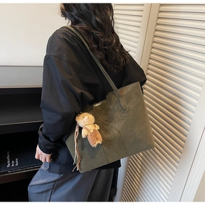 Detail of dark green tote bag in matte PU leather with brown plush bear charm
