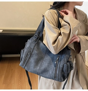Detail of a large dark gray vintage tote bag with side pockets and decorative zippers