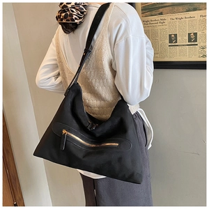 Detailed view of a large black suede tote bag with gold zipper carried by a model