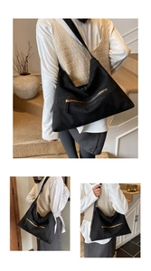 Detail of black suede tote bag with metal zipper accent and large storage capacity