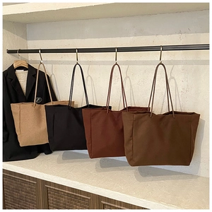 Detailed display of four large canvas tote bags in earthy tones hanging on a white wall