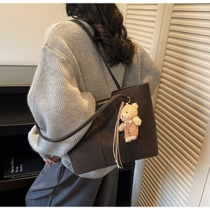 Detail of deep brown suede tote bag with cute bear pendant and long shoulder straps